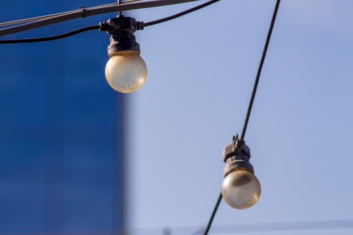 Two round LED bulbs hanging from a wire against a blue background.