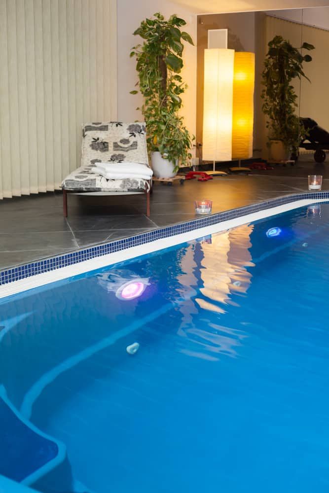 A cozy indoor space with a pool, lounge chair, and glowing lights.