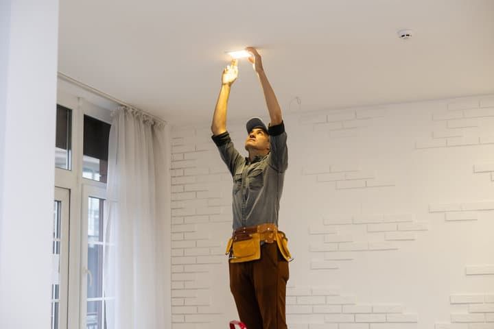 A person installs an LED light on a ceiling in a modern room.