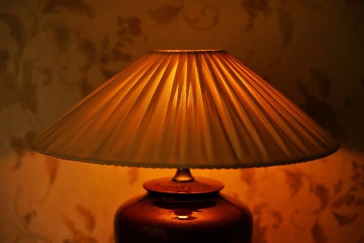 A warm-toned lamp with a pleated lampshade illuminating a cozy space.