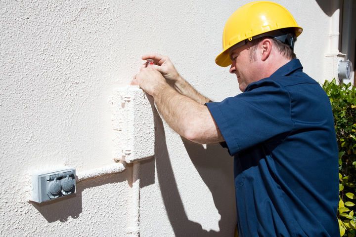 A worker in a hard hat installing LED lighting on a textured wall.