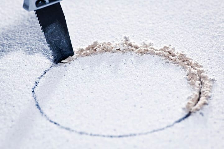 A circular pattern is scratched into white sand with a serrated tool.