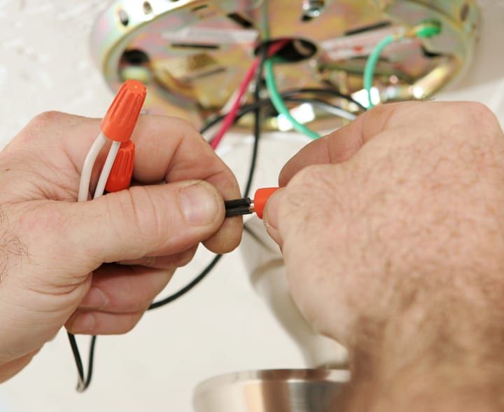 Hands connecting electrical wires for LED light installation.