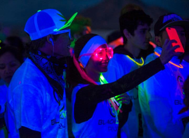 People wearing neon accessories under blacklight, enjoying a vibrant event.