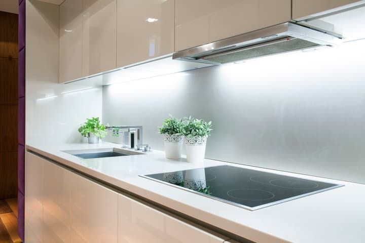Modern kitchen featuring LED lighting, a cooktop, and potted plants.