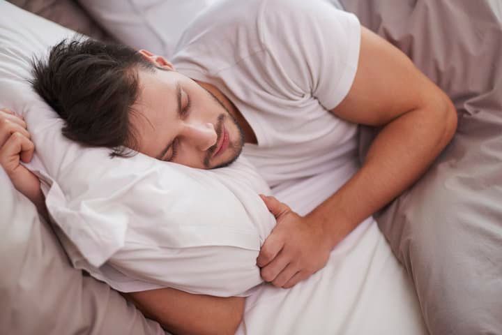 Man sleeping peacefully on a pillow in a cozy bedroom setting.