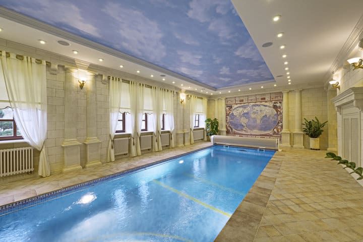 Indoor pool area with decorative lighting, soft curtains, and a ceiling mural.