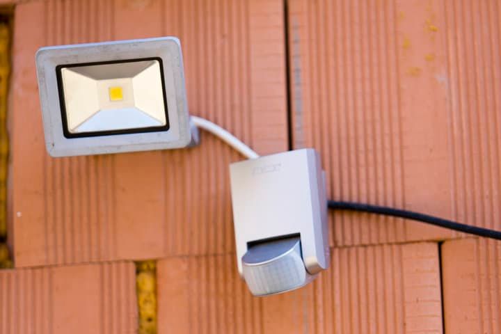 A square LED floodlight mounted on a wall with a switch nearby.