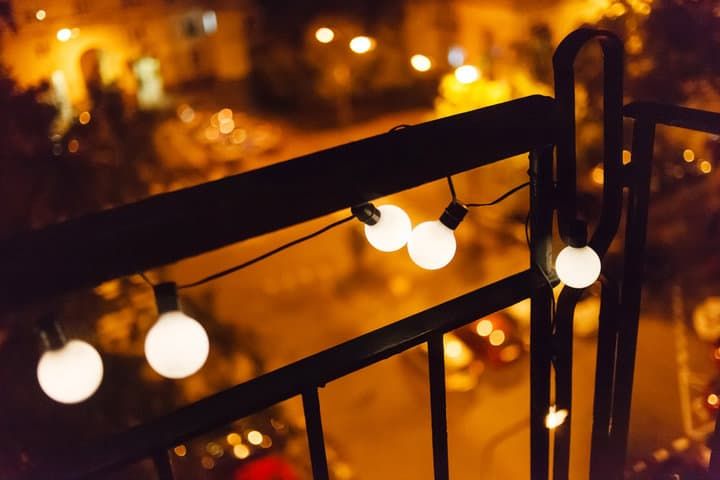 Decorative LED string lights hanging from a balcony railing at night.