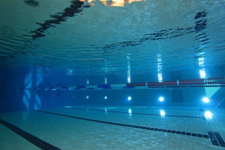 Underwater view of a swimming pool illuminated by bright LED lights.