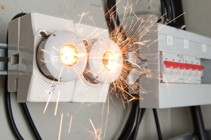 Two electrical sockets sparking, highlighting safety issues in LED lighting setups.