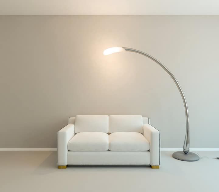 A contemporary white sofa beside a stylish arc floor lamp.
