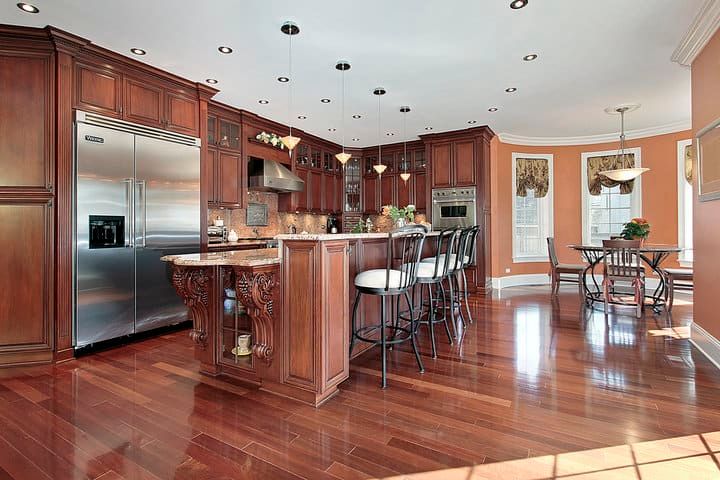 Brightly lit kitchen with wooden cabinets, island, and stainless steel appliances.