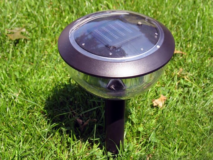 A solar-powered LED garden light on green grass.