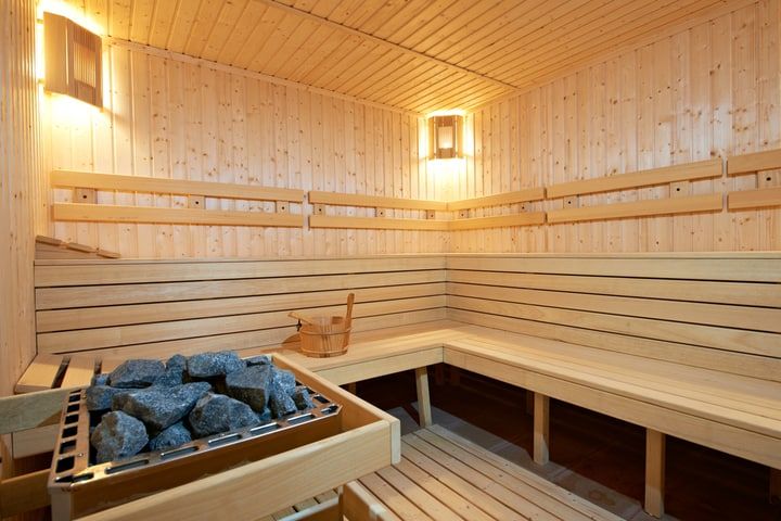 Interior of a sauna with wooden benches and stone heater.