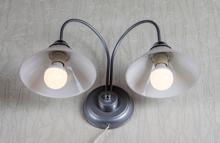 Two modern lamps with white shades and LED bulbs on a textured wall.