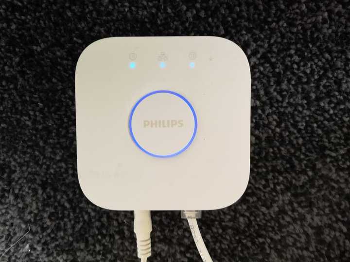 A white Philips lighting control device with indicator lights on a dark textured surface.