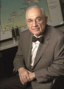 A man in a suit sits in front of a chart displaying LED technology.
