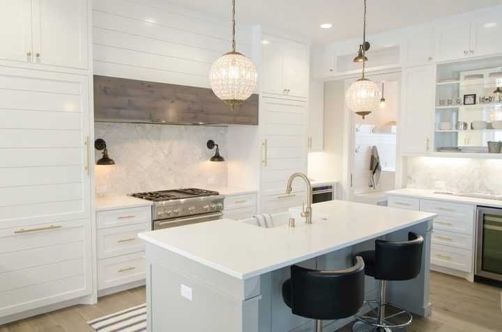 Modern kitchen featuring white cabinetry, marble backsplash, and stylish pendant lights.