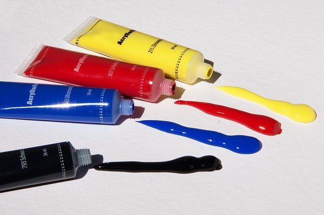 Colorful tubes of acrylic paint with vibrant paint blobs on a white surface.