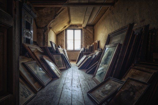 Dimly lit attic with leaning picture frames against the walls.