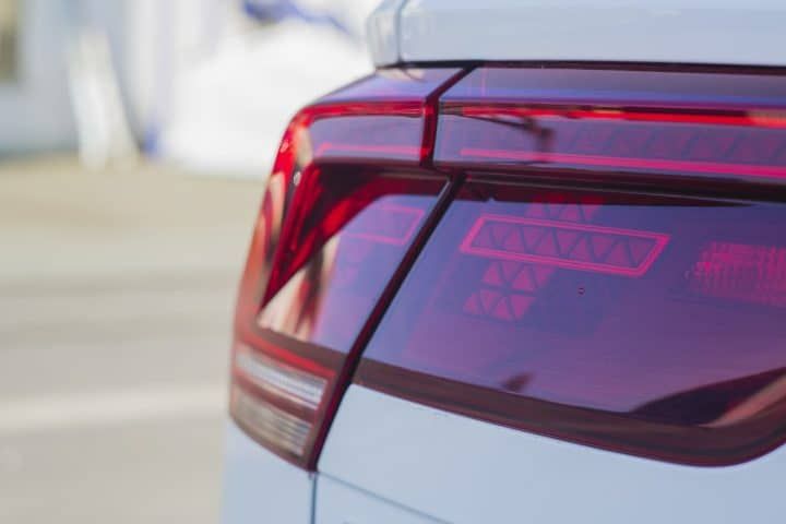 Close-up of a car's LED tail light with intricate designs and vibrant red illumination.