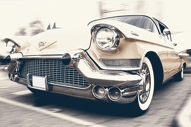 Classic vintage car with chrome detailing parked on a city street.