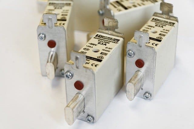 Several electrical circuit breakers arranged closely on a white surface.