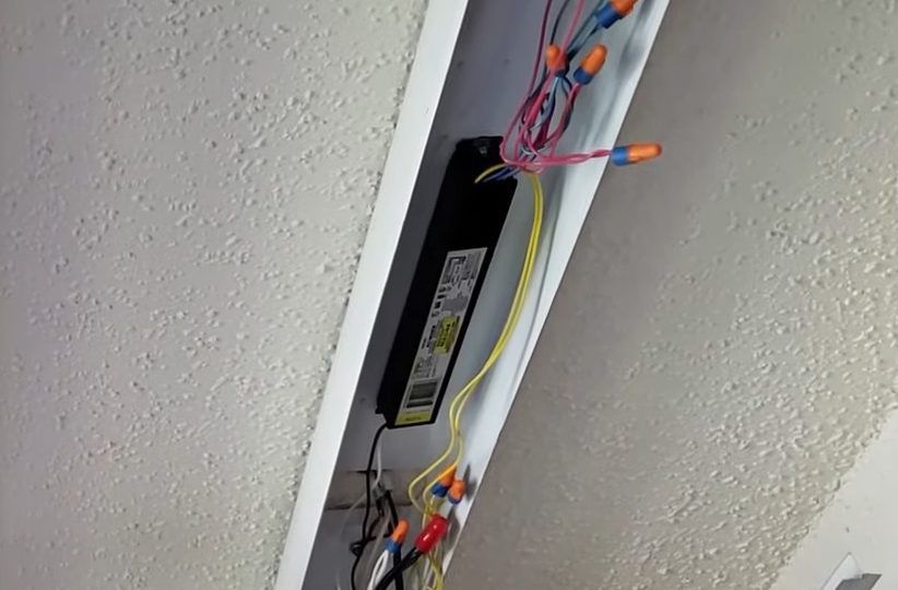A LED driver visible in a ceiling light fixture with multiple wiring connections.