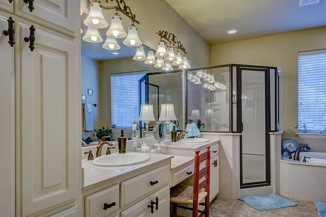 Well-lit modern bathroom featuring elegant fixtures, a shower, and dual sinks.