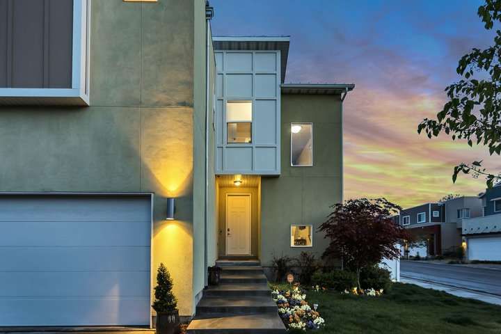 Modern house exterior illuminated by warm LED lights at dusk.