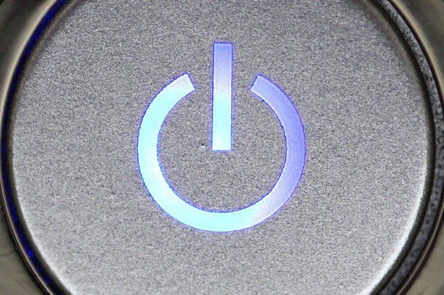 A close-up of a blue illuminated power button on a metallic surface.