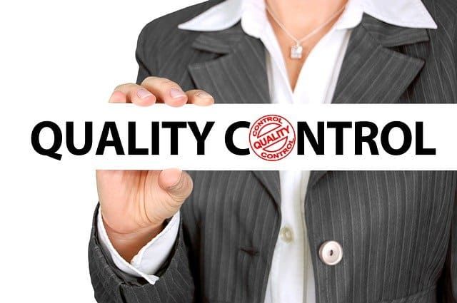 A businesswoman holding a sign that reads 'QUALITY CONTROL' in bold letters.