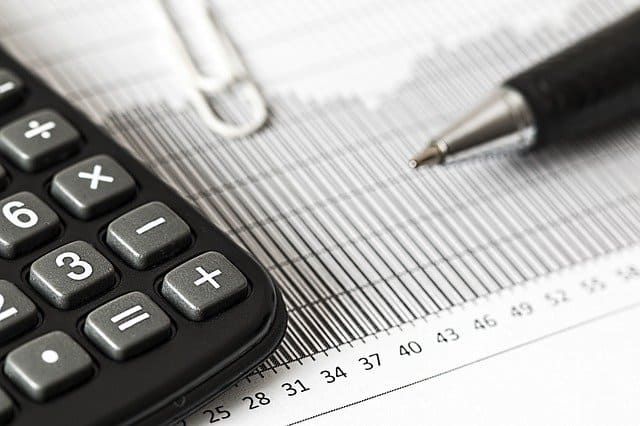 A calculator, pen, and paper with graphs for financial analysis.