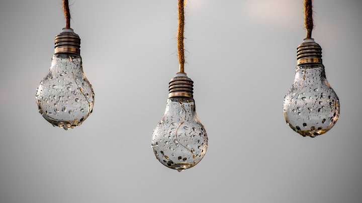 Three hanging light bulbs with water droplets on their surface.