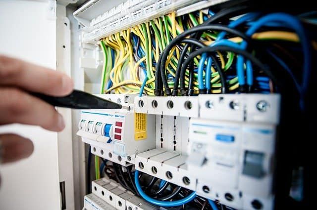 A hand adjusting electrical components within a circuit breaker panel.