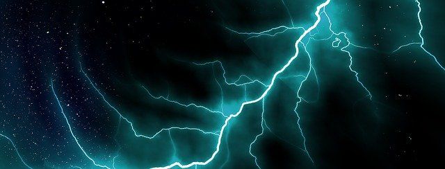 Bright blue lightning bolts against a dark, cloudy background with stars.