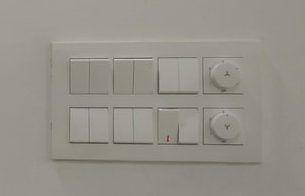A white wall switch panel with various toggles and dimmers.
