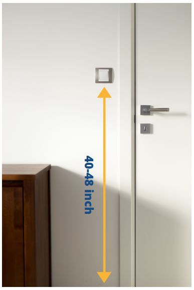 Light switch mounted on a white wall next to a wooden cabinet.