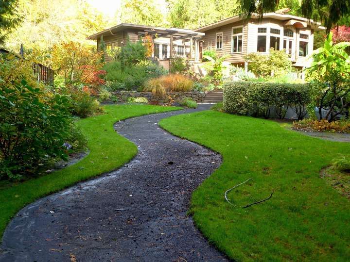 Curved pathway through a lush garden leading to a house.