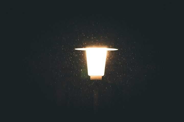 A bright white LED light shining in the dark surrounded by falling rain.