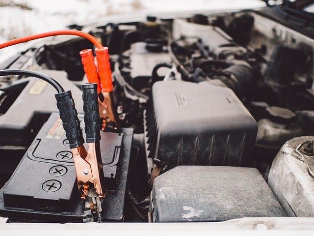 Close-up of a car battery with jumper cables connected to it.