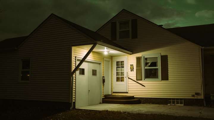 A house exterior at night with illuminated porch lights and dark surroundings.