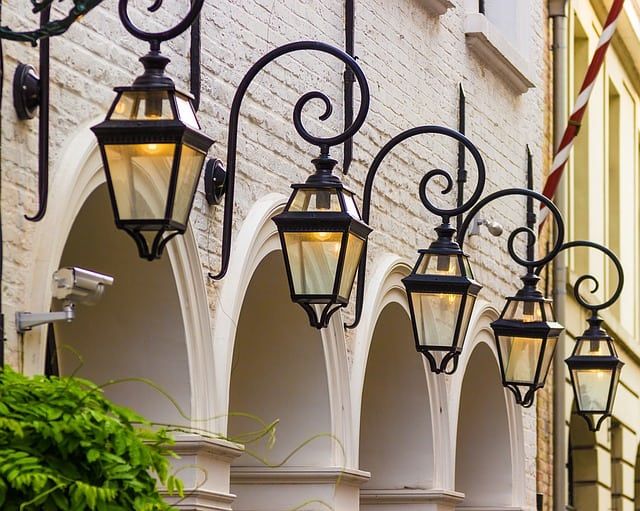 Row of elegant black lanterns hanging beside arched doorways on a brick wall.
