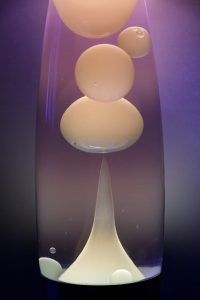 Colorful liquid with spherical bubbles rising and falling in a lamp.