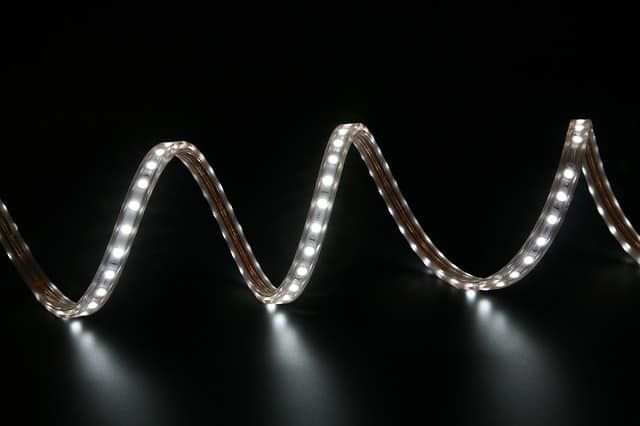 Flexible LED strip lights arranged in waves on a dark background.