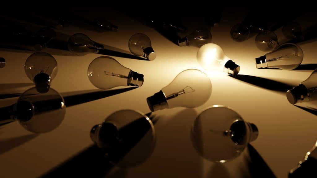 Multiple light bulbs scattered on a flat surface, casting shadows.