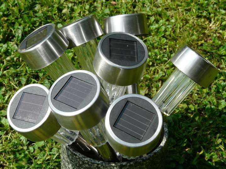 Collection of solar-powered garden lights standing in a pot on green grass.