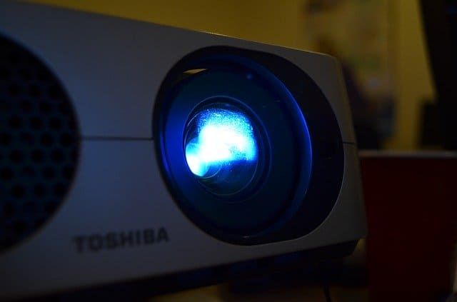 Close-up of a Toshiba projector emitting a blue light beam.