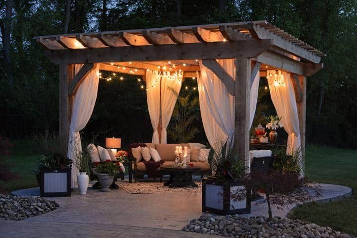 Cozy outdoor sitting area with LED string lights, plants, and soft furnishings.